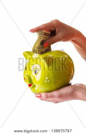 Girl's hand holding money box. Green piggy bank and dollars. You can efford luxury vacation. Don't spend everything at once.