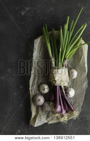 purple spring onions on dark table background
