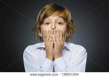 Closeup Portrait of handsome boy with astonished expression while standing against grey background.