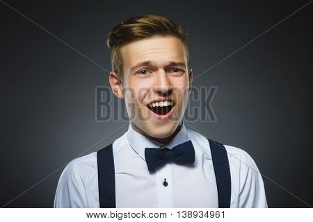 Closeup Portrait of handsome boy with astonished expression while standing against grey background.