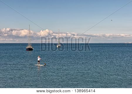 Swanage Dorset UK - July 2016. Eldery male paddles a paddleboard at the sea