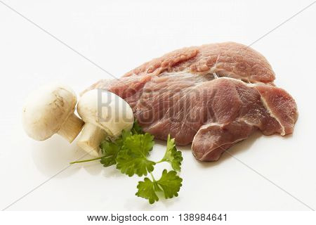 red raw meat piece with vegetables and greens on a white background