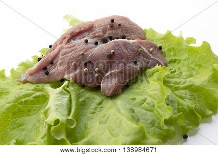 red raw meat piece with vegetables and greens on a white background
