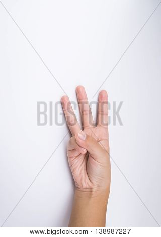 child hand shows the number three on white background