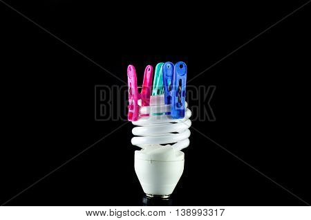 Energy saving lamp The clothespin isolated on black background.