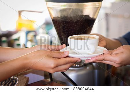 A Woman Is Serving Coffee To A Client In A Coffee Shop.