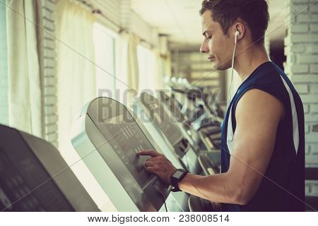 Young Sporty Man Choosing Program On Threadmill In Gym