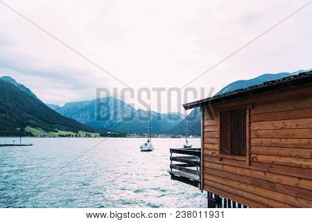 Scenic View Of Achensee Lake In Austria At Sunset With Wooden Cottage On Foreground