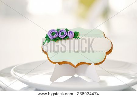 Cute Gingerbread Cookie Sugared With Blue And Green Glaze Flowers And Pearls Stands On A White Plate