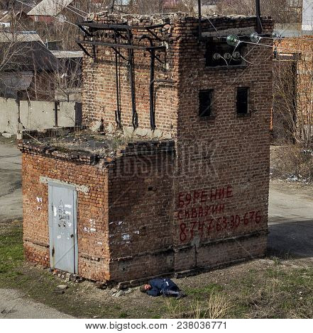 Kazakhstan, Ust-Kamenogorsk, april 21, 2018: High voltage power transformer substation. Old building. Sleeping homeless