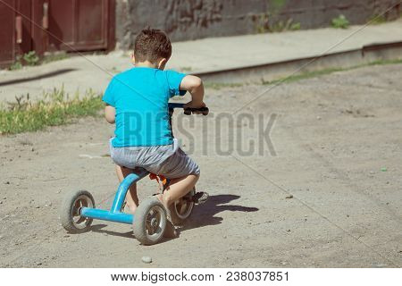 A Boy Riding A Tricycle In Nature .