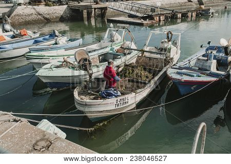 March 24th, 2018 - Olhao, Portugal: Fisherman Working And Repairing Nets In His Boat, Docked At Olha
