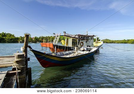 Traditional Malaysian Fisherman Boat Moored Near The Riverbank Over Blue Sky Background