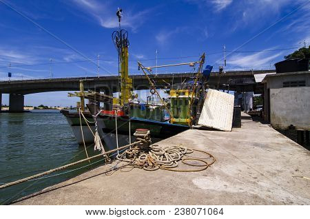 Traditional Fishing Boats Moored At The Harbour Over The Bridge And Blue Sky Background During Mid D
