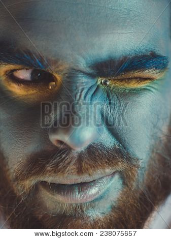 Portrait of a man with a blue make-up on his face. Stage make-up, like an alien, fantasy