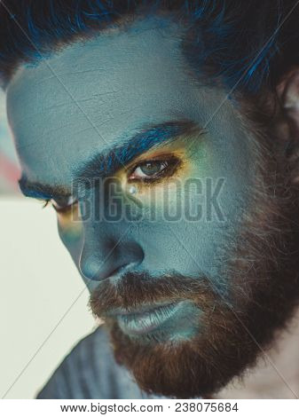 Portrait of a man with a blue make-up on his face. Stage make-up, like an alien, fantasy