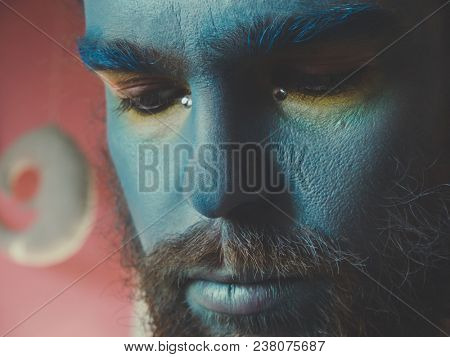 Portrait of a man with a blue make-up on his face. Stage make-up, like an alien, fantasy