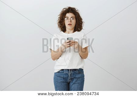 Cannot Move From Shock. Portrait Of Stunned Amazed Charming Brunette In Eyewear And Earphones, Holdi
