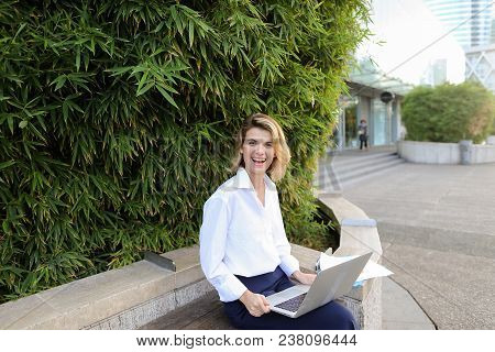 Female Secretary Working With Laptop And Papers In Open Air Near Green Plant. Concept Of Busines, Mo