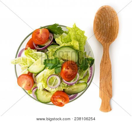 Vegetable Salad In A Bowl And A Wooden Spoon On A White Background. The View From The Top.