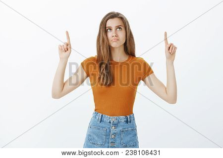 Not Bad Copy Space. Pleased Attractve European Female In Stylish Outfit, Raising Index Fingers, Look