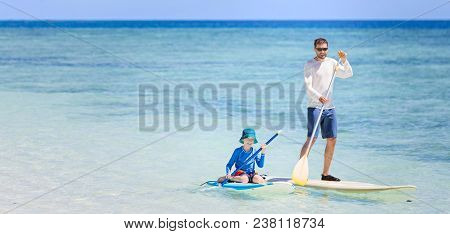 Panorama Of Happy Family Of Two, Father And Son, In Rashguards Enjoying Stand Up Paddleboarding, Hea