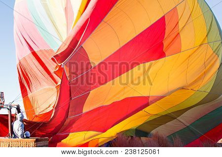 Family Of Two In The Basket Looking At Hot Air Baloon Filling Up With Air Ready For Take Off, Advent