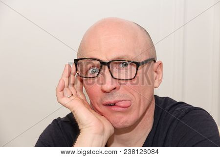 Adult Bald Man In Glasses Shows Tongue
