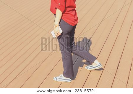 Attractive Woman Holding Smart Phone While Walking Down The Stairs.