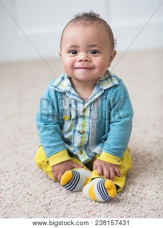 Beautiful smiling diverse baby boy portrait. Full length photo of an adorable child sitting indoors