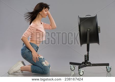 Young Brunette Woman With Raised By The Wind Machine. Studio Shot Over Gray Background
