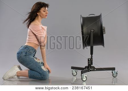 Young Brunette Woman With Raised By The Wind Machine. Studio Shot Over Gray Background