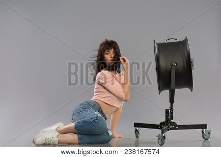 Young Brunette Woman With Raised By The Wind Machine. Studio Shot Over Gray Background