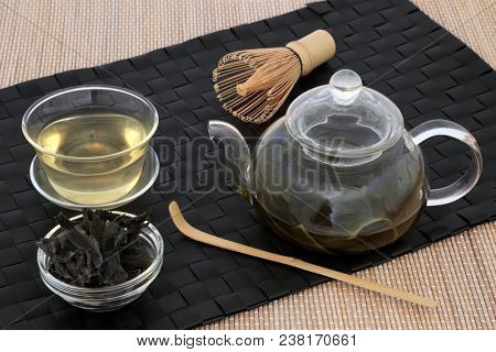 Japanese sencha wakame seaweed  tea with glass teapot and cup, dried leaves, stirrer and whisk on bamboo background. Has many health benefits and is very high in minerals.
