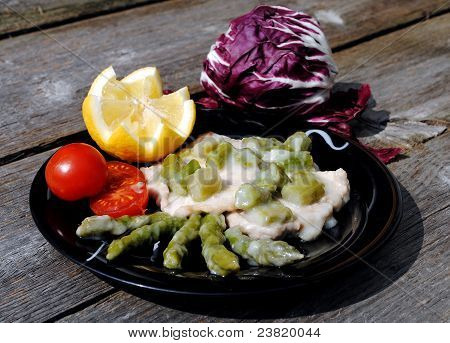 Scaloppina di vitello nel piatto nero con pomodori