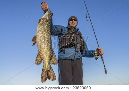 Happy Fisherman Holding Big Pike Fish Trophy And Fishing Rod