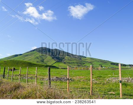 Typical New Zealand Rolling Countryside Farm Fields From Road To Hillside.