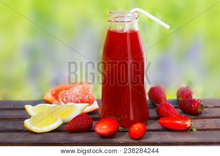 Fresh Summer Strawberry Juice In A Botlle And Ripe Berries And Citrus Fruit On A Wooden Table. Sunny