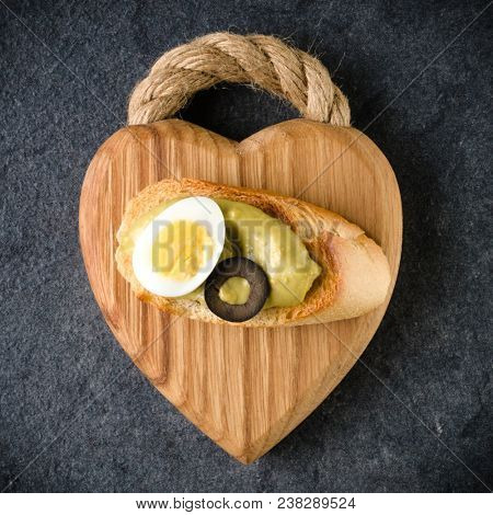 Open faced sandwich canape or crostini on a wooden serving board on dark stone background closeup. Top view. Vegetarian tartarine.