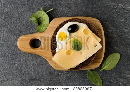 Open  faced cheese sandwich canape or crostini on a wooden serving board  on dark stone background closeup. Top view.