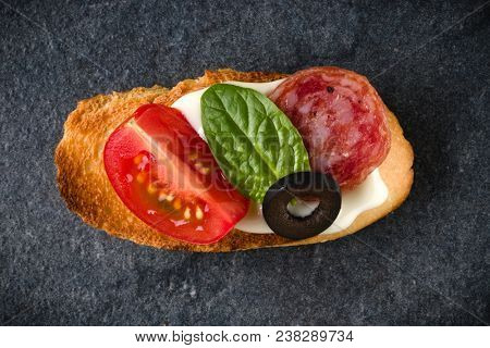 Open faced sandwich canape or crostini on dark stone background closeup. Top view.
