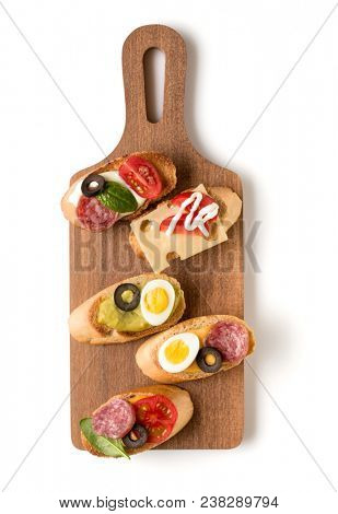 Open faced sandwich canape or crostini on a wooden serving board isolated on white background closeup. Top view.