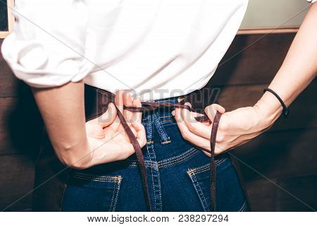 Barista Tying Up Her Apron Around The Waist