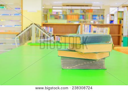 Old Book And Heap Treatise In School Library On Table Green. Blurry Bookshelves Background. Educatio