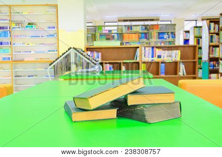 Old Book And Heap Treatise In School Library On Table Green. Blurry Bookshelves Background. Educatio