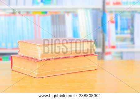 Old Book Red And Heap Treatise In School Library On Wooden Table. Blurry Bookshelves Background. Edu