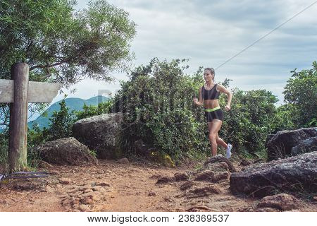 Young Sportswoman Cross Country Running On Dirty Rocky Footpath In Mountains In Summer. Fit Girl Jog