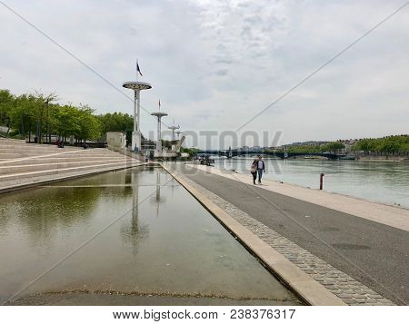 LYON, FRANCE - APRIL 28, 2018: Pedestrians walk beside the river RhÃ´ne in Lyon, France.