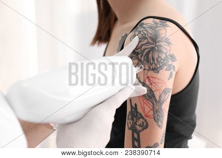 Cosmetologist with patient and professional tattoo removal laser in salon