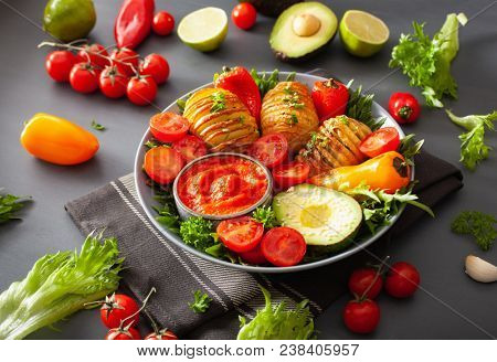 vegan buddha bowl. healthy lunch bowl with hasselback potato, avocado, tomato, bell peppers and pepper sauce